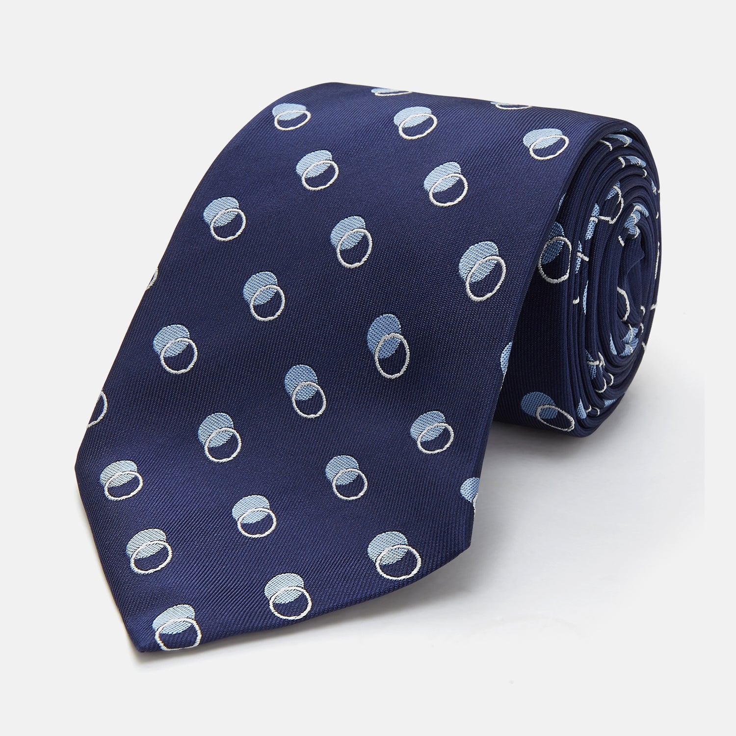 View 1 of product The Turnbull & Asser Navy Multi Circle Silk Tie showcases overlapping light blue and white rings on navy silk—a stylish choice to elevate bold shirts or bring visual interest to your summer look.