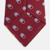 View 4 of product The Turnbull & Asser Red Multi Circle Silk Tie features small blue and white rings on red silk, making it ideal for pairing with bold shirts or adding vibrant flair to summer looks. Shown rolled at one end against a plain white background.