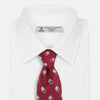 View 2 of product The Turnbull & Asser Red Multi Circle Silk Tie features small blue and white rings on red silk, making it ideal for pairing with bold shirts or adding vibrant flair to summer looks. Shown rolled at one end against a plain white background.