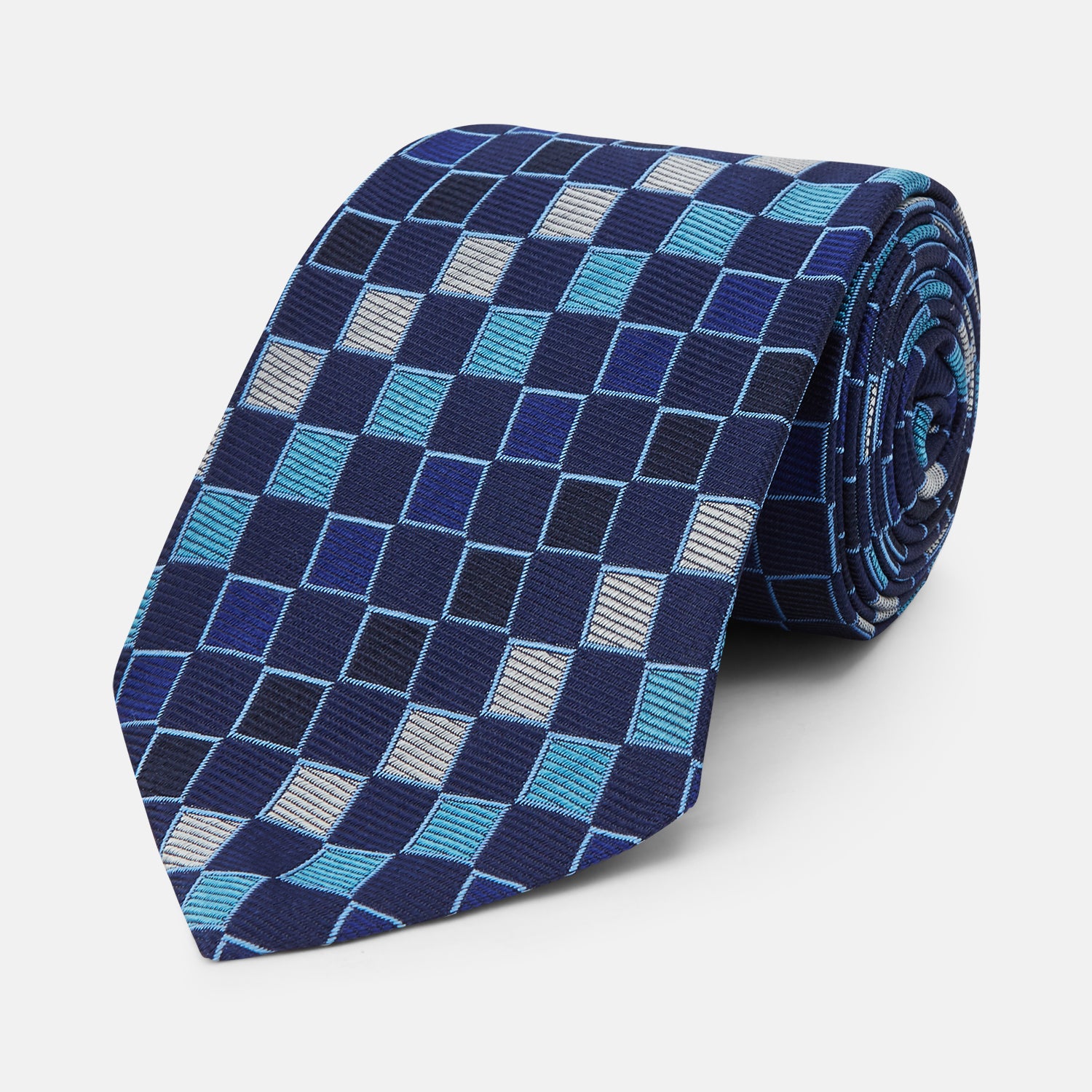 View 1 of product The Blue Multi Check Silk Tie by Turnbull & Asser features a geometric checked pattern in blue, light blue, and silver on dark navy—ideal for pairing with bold shirts.