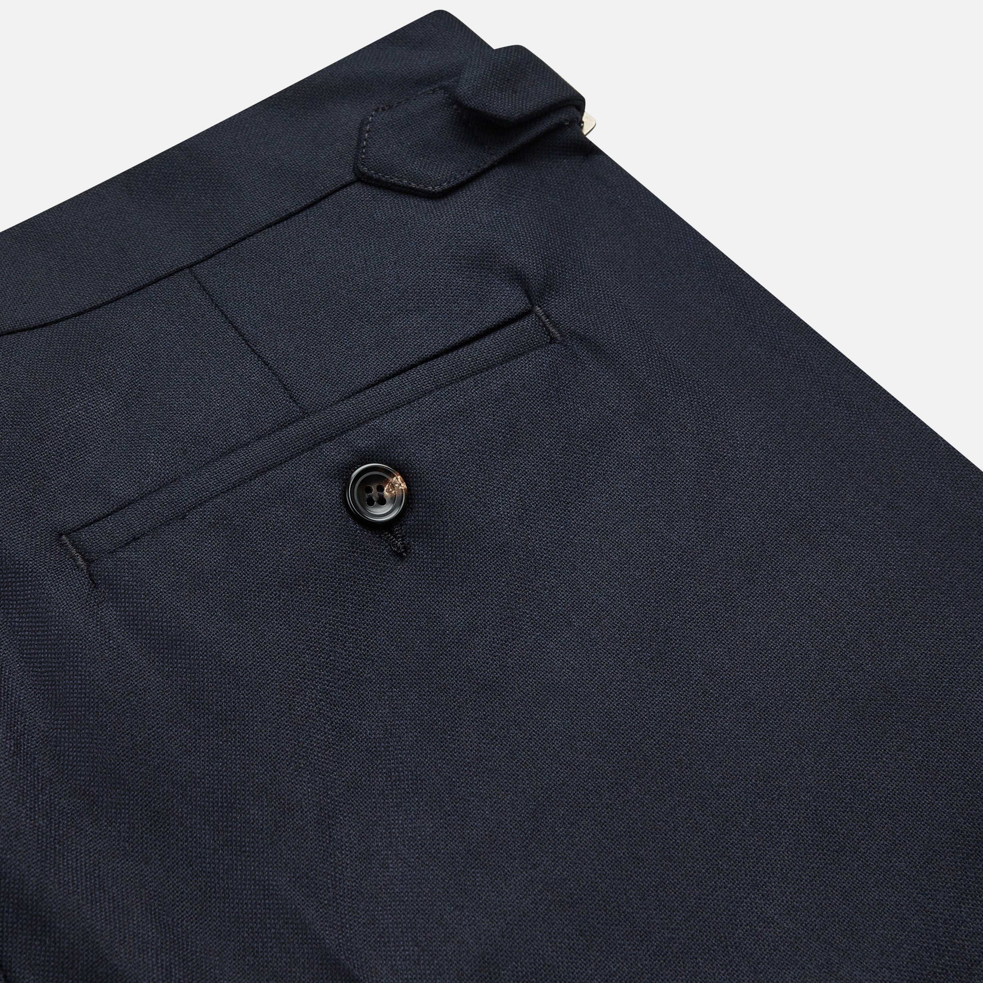 View 2 of product The Navy Escorial Wool Jonathan Trousers by Turnbull & Asser, featuring side adjusters, front pleats, and side pockets, are shown laid flat on a white background.