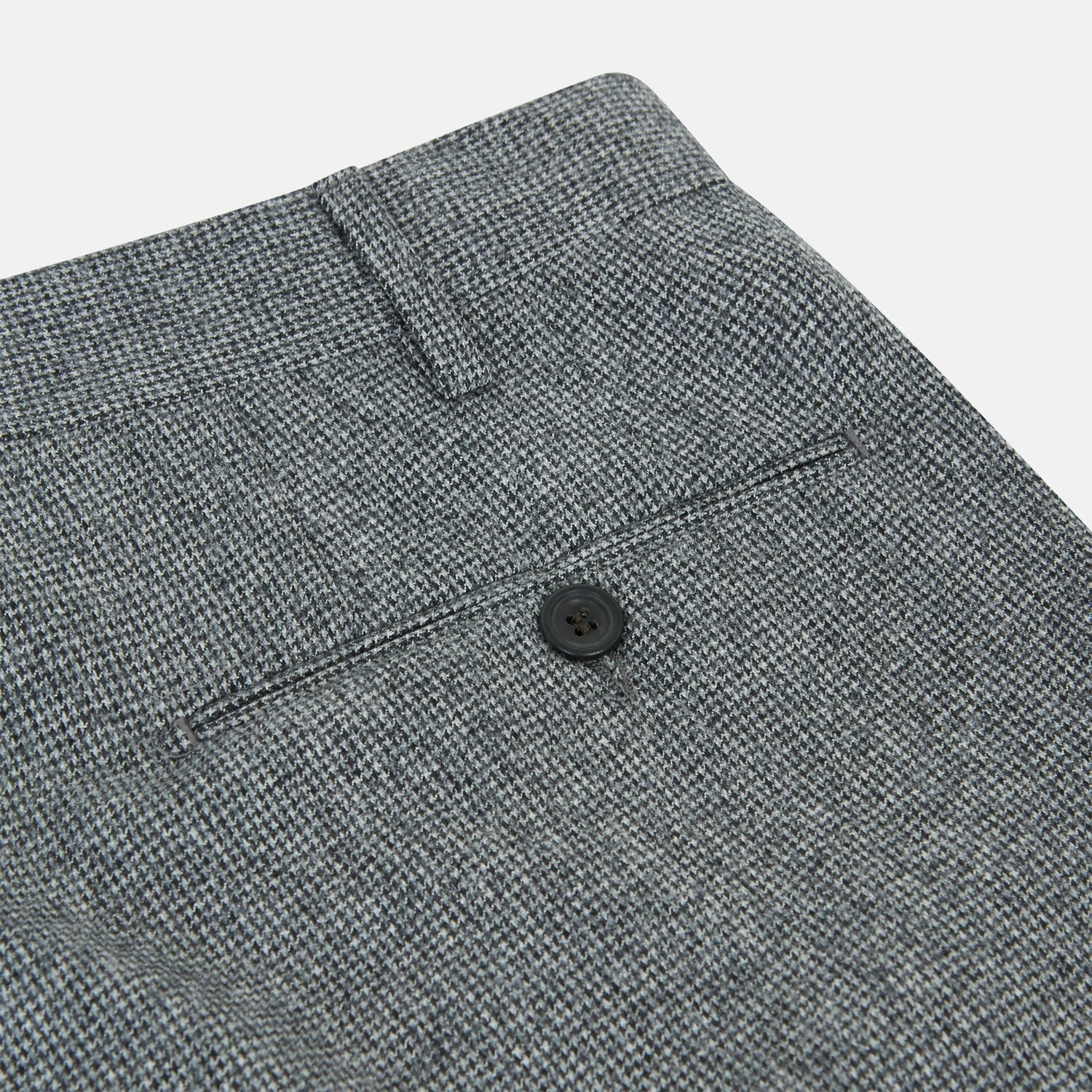 View 3 of product A person wears Turnbull & Asser Grey Puppytooth Wool Manson Trousers, a white dress shirt with rolled-up sleeves, and black shoes, standing against a plain beige background.