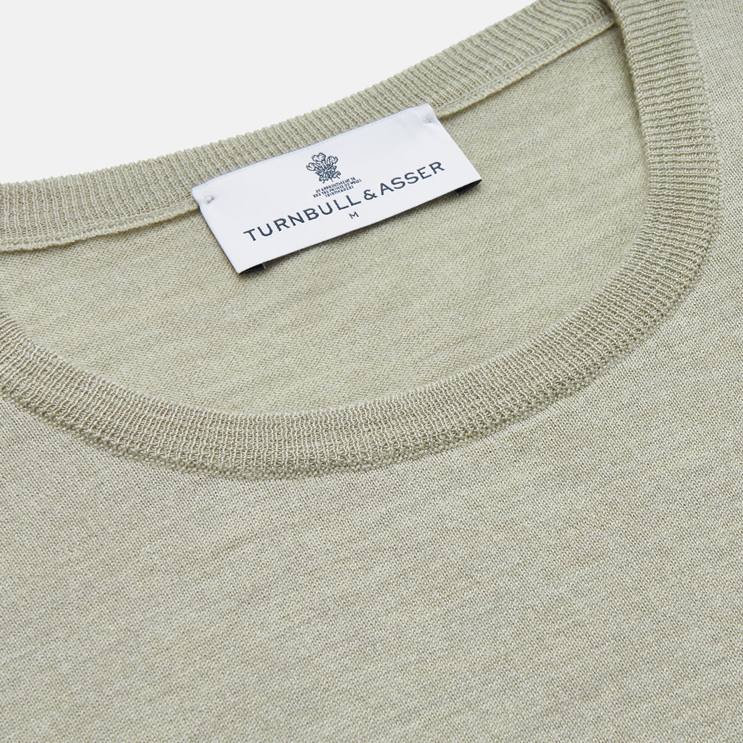 View 2 of product The Light Green Kingston Merino Crew Neck Jumper by Turnbull & Asser is laid flat, displaying its classic design with ribbed cuffs, hem, and neckline.