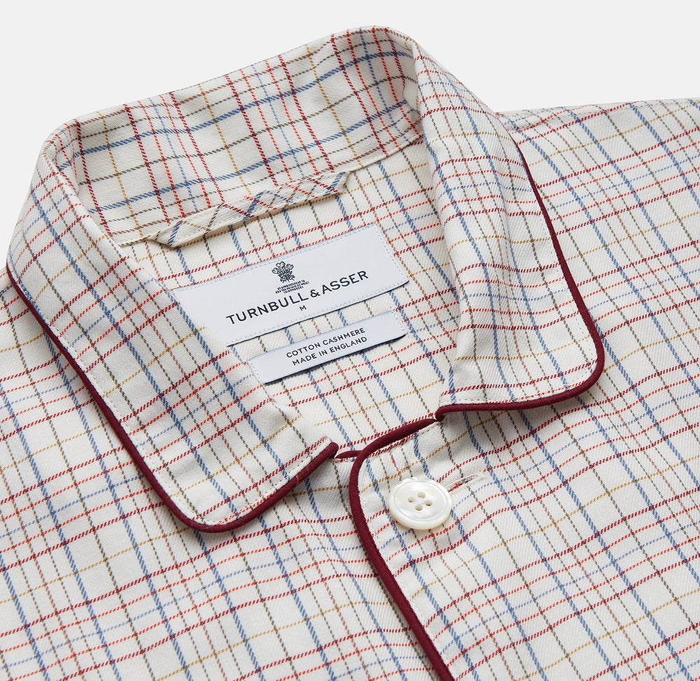 The Turnbull & Asser Red Multi Check Cotton-Cashmere Modern Pyjama Set, made in England, features a long-sleeve button-up shirt and pants in red and gray plaid with dark piping, crafted from soft Italian cotton-cashmere.