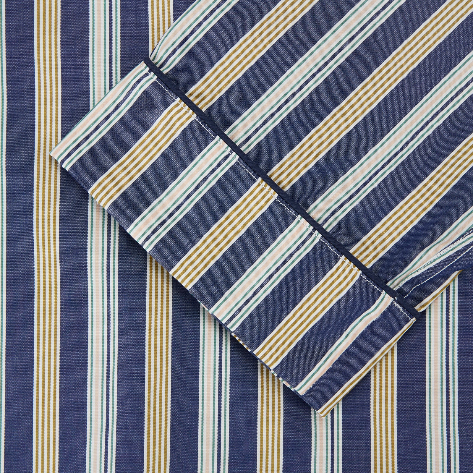 View 3 of product Turnbull & Asser's Blue Multi Stripe Cotton Modern Pyjama Set features a camp collar shirt with white buttons, front pocket, and long sleeves. Both pieces showcase classic blue and beige stripes for a timeless look.