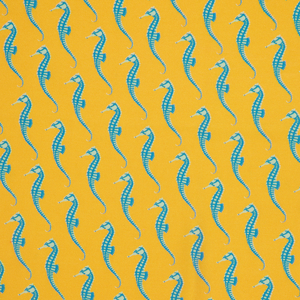 The Turnbull & Asser Yellow & Blue Seahorse Silk Pocket Square features a repeating seahorse pattern in diagonal rows and is handprinted in England, with branding in two corners.