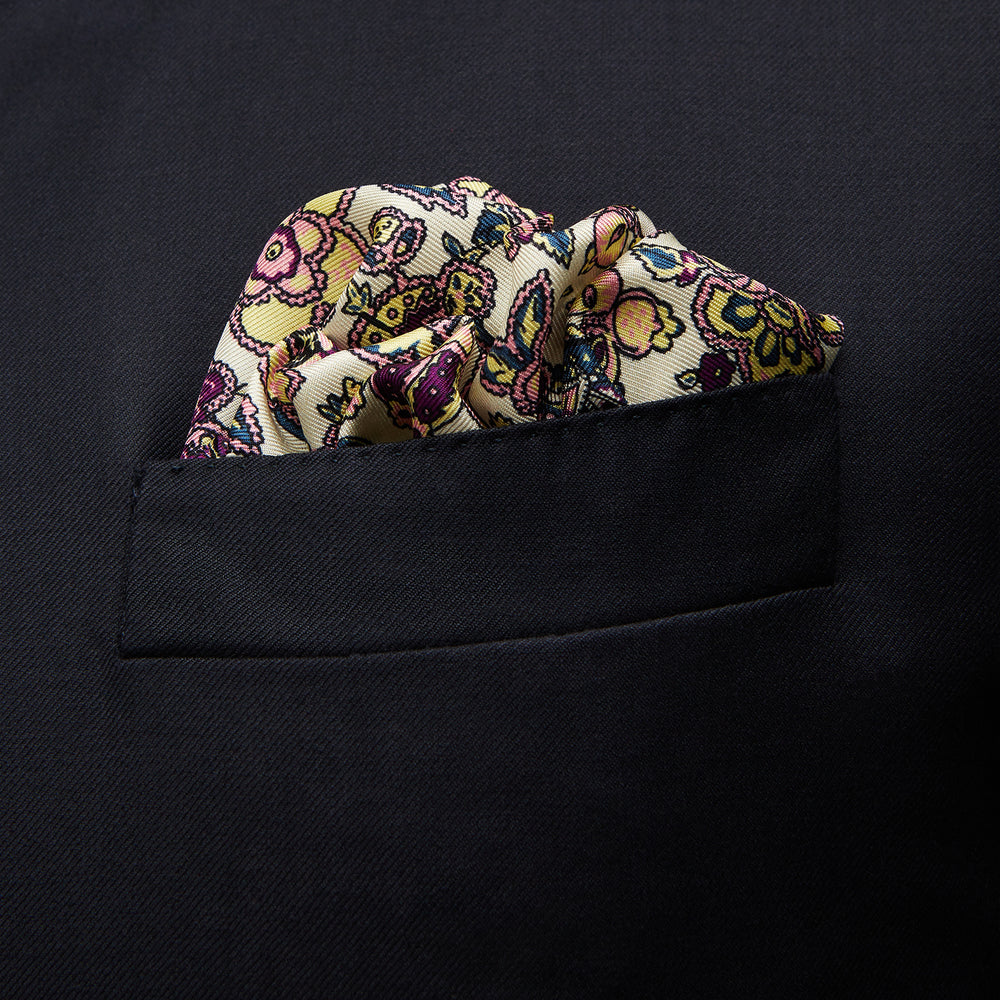 The White Floral Silk Pocket Square by Turnbull & Asser is crafted in England from silk, featuring a floral and paisley design in pink, purple, and gold with a navy border and the "TURNBULL & ASSER" logo in the corner.