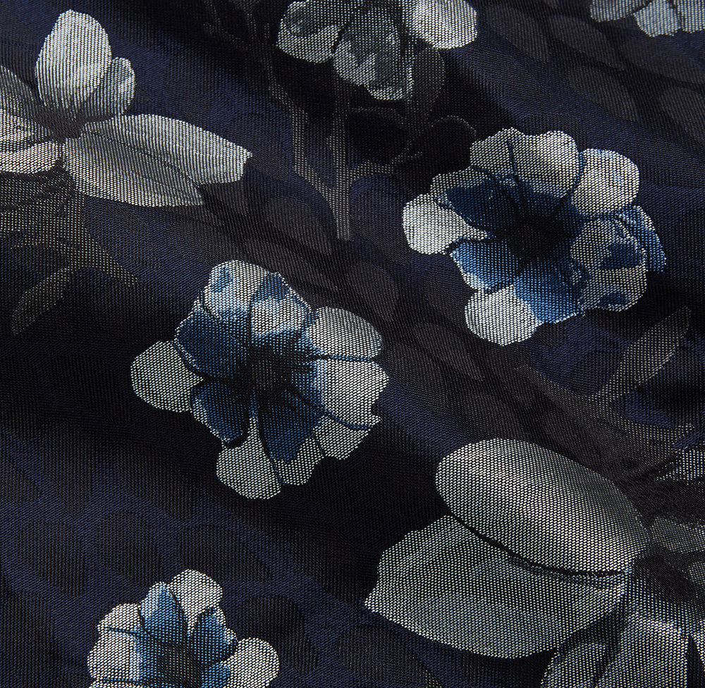 The Navy Floral Silk Jacquard Pierce Gown by Turnbull & Asser features a shawl collar, long sleeves, matching fabric belt, and elegant grey and blue floral design.