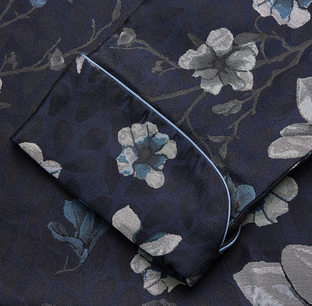 The Navy Floral Silk Jacquard Pierce Gown by Turnbull & Asser features a shawl collar, long sleeves, matching fabric belt, and elegant grey and blue floral design.
