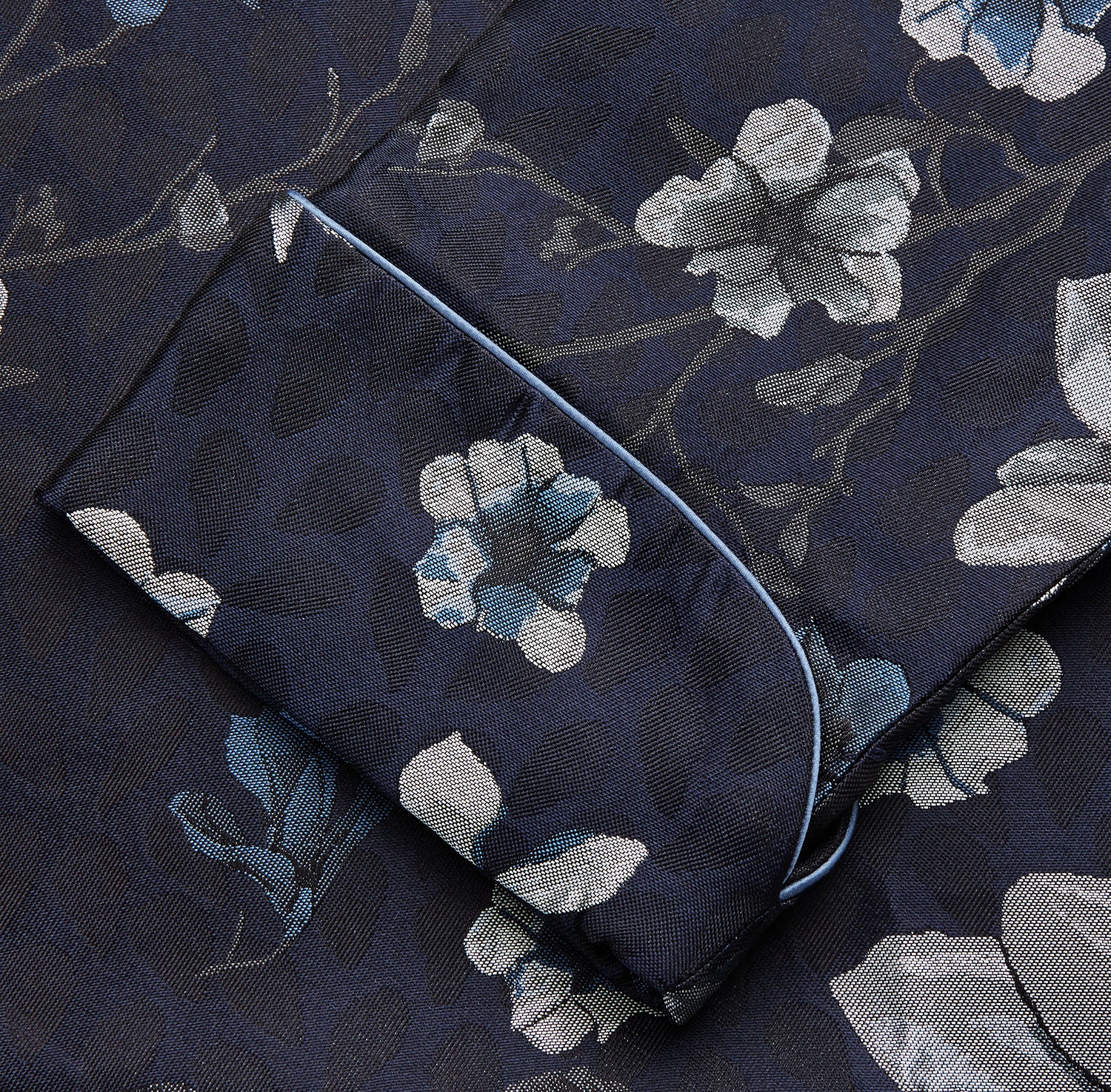 View 4 of product The Navy Floral Silk Jacquard Pierce Gown by Turnbull & Asser features a shawl collar, long sleeves, matching fabric belt, and elegant grey and blue floral design.