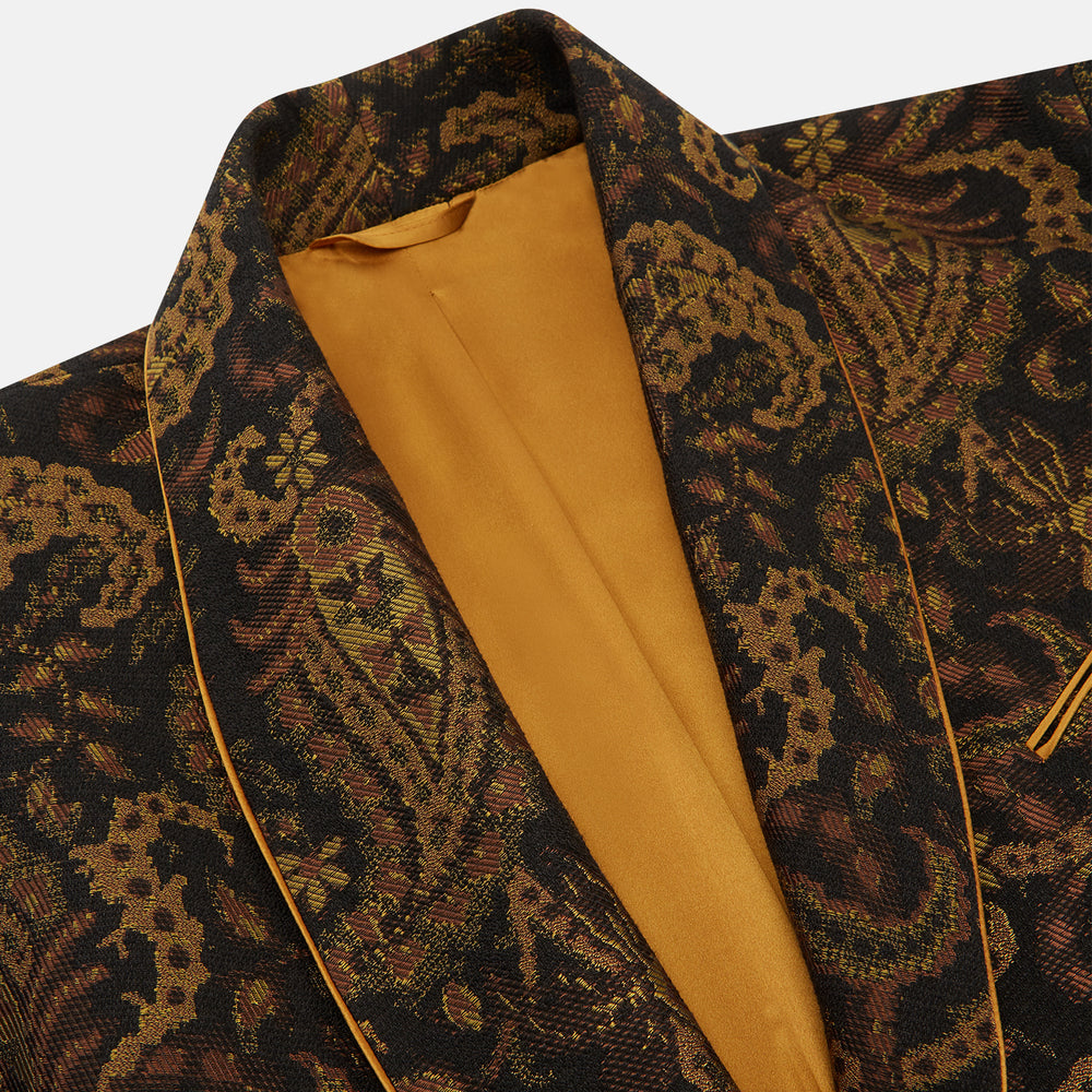 The Turnbull & Asser Gold Multi Floral Cotton, Wool & Silk Jacquard Pierce Gown features a shawl collar, matching belt, golden lining, and an elegant floral pattern in luxurious black, gold, and brown tones.