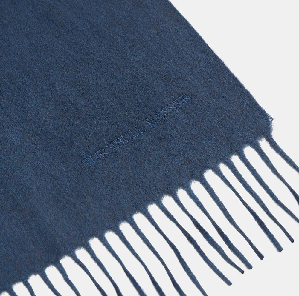 The Turnbull & Asser Slate Blue Purled Fringe Cashmere Scarf, neatly folded on a white background, is a stylish winter accessory.