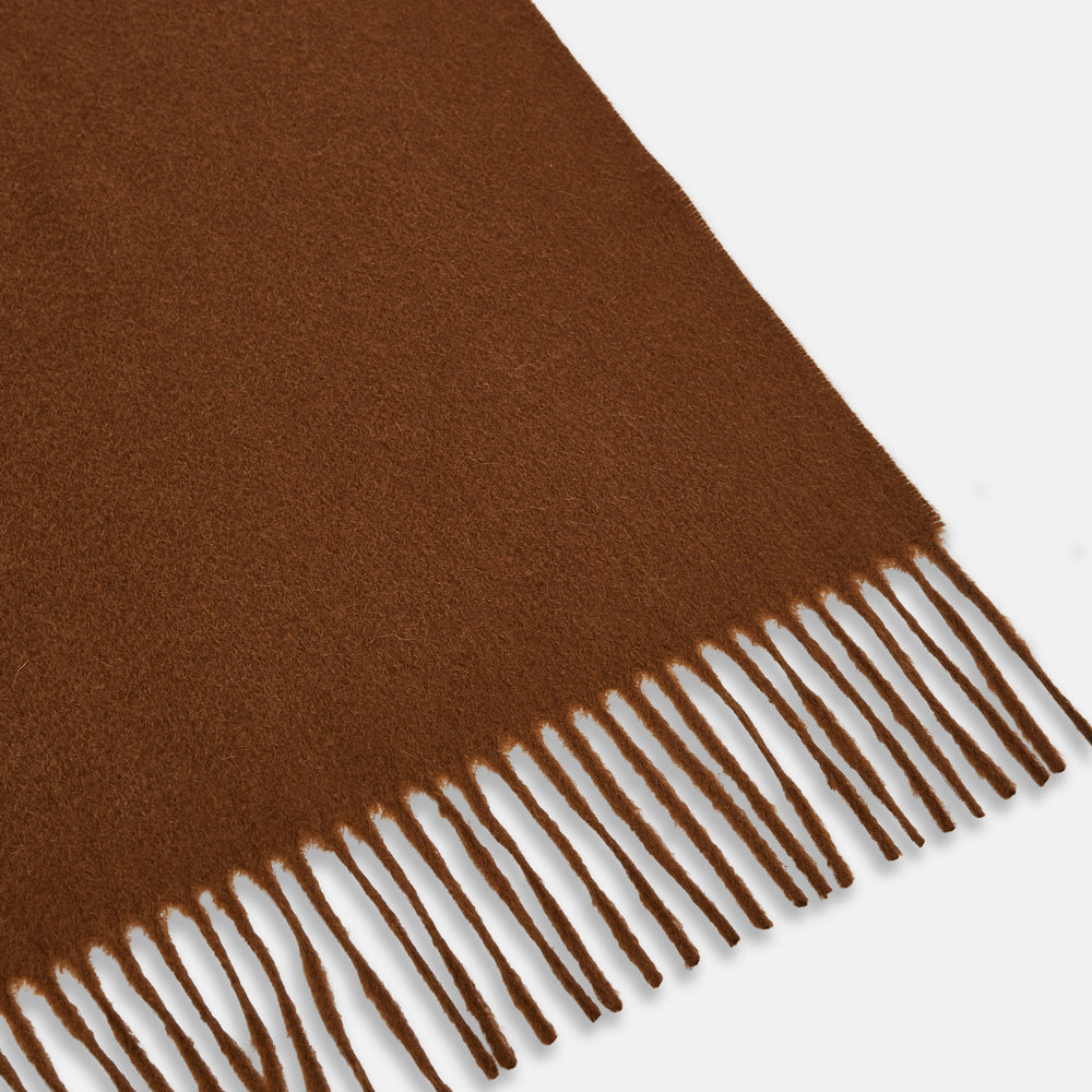 The Turnbull & Asser Rust Cashmere Wilde Stole Scarf is oversized with a soft texture, features short fringe detailing on the ends, and is shown loosely tied against a plain white background.