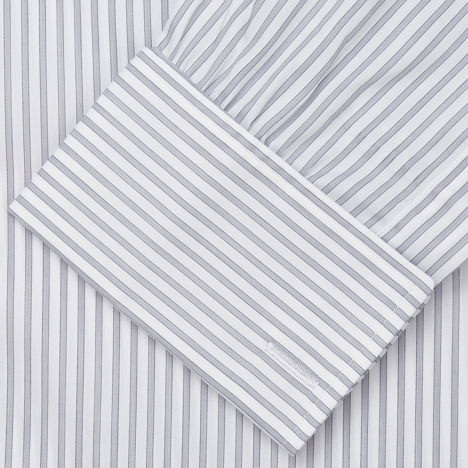 View 4 of product A man wearing the Turnbull & Asser Grey Multi Stripe Regular Fit Twill Shirt with T&A Collar and Double Cuffs stands against a beige background, one hand in his pocket, looking at the camera.