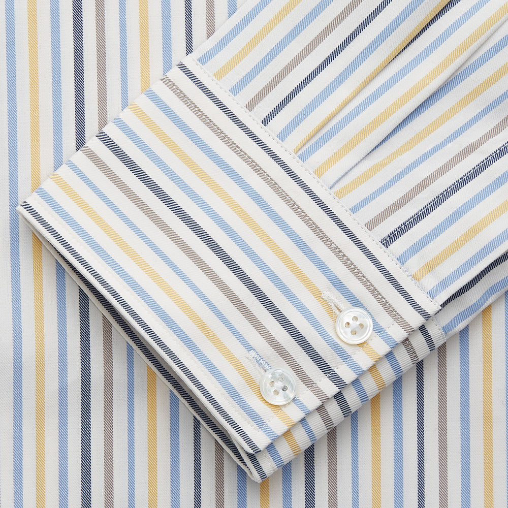 Turnbull & Asser’s Yellow Multi Stripe Tailored Fit Shirt features a Kent collar, blue, yellow, and white stripes on a light background, 2-button cuffs, and a curved hem for a refined look.