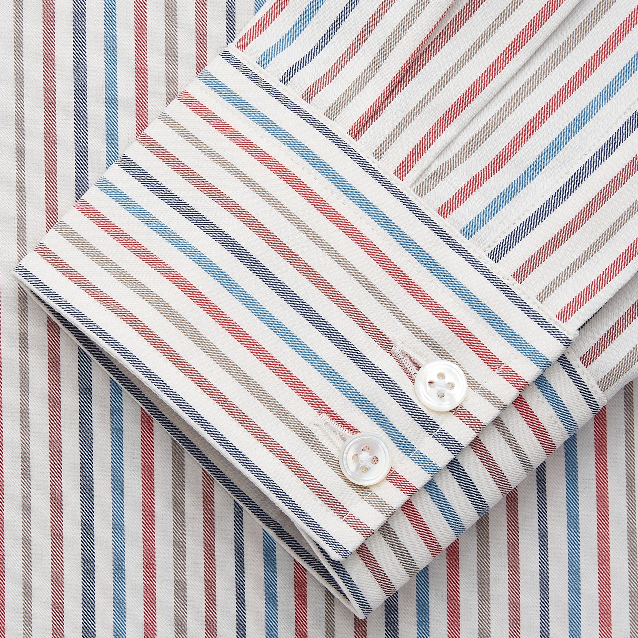 View 3 of product The Turnbull & Asser Burgundy Multi Stripe Tailored Fit Shirt features a Kent collar and 2 button cuffs, with vertical stripes on a light background. The shirt is neatly laid flat on a white surface.