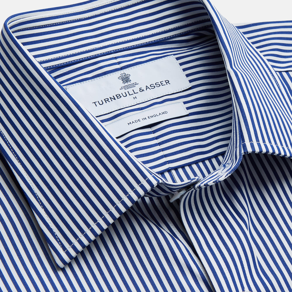The Turnbull & Asser Navy & White Stripe Weekend Fit Shirt features a Derby collar, 1-button cuffs, front chest pocket, vertical stripes, and white buttons. Displayed flat on a white background.