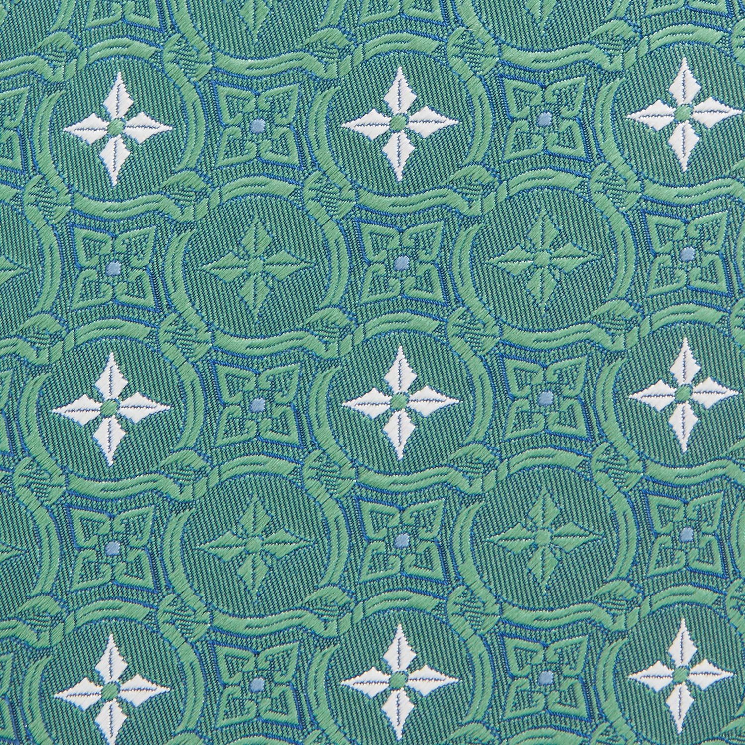 View 3 of product The Turnbull & Asser Green Multi Neat Silk Tie, handmade and featuring a white and light blue geometric pattern, is shown rolled up on a plain white background.
