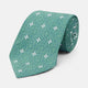 The Turnbull & Asser Green Multi Neat Silk Tie, handmade and featuring a white and light blue geometric pattern, is shown rolled up on a plain white background.