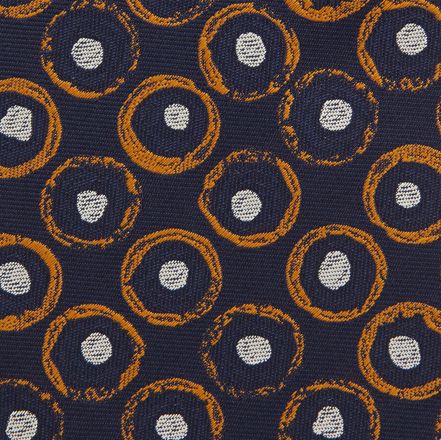 View 3 of product The Turnbull & Asser Orange Multi Circle Printed Silk Tie features navy blue silk with orange circles and white ovals, perfect for elevating any formal outfit. Shown on a plain white background.