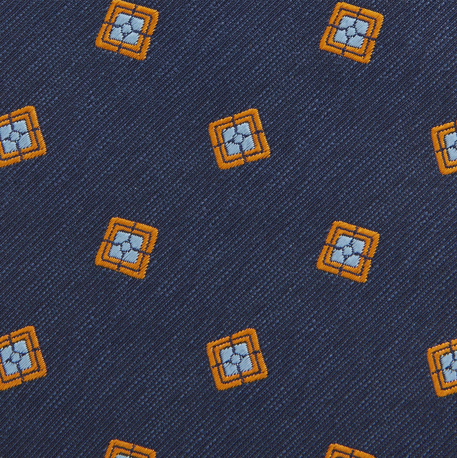 View 3 of product The Turnbull & Asser Orange Multi Geo Silk Tie, featuring a vibrant geometric pattern, is showcased rolled up on a plain white background—an elegant piece from our autumn-winter collection.