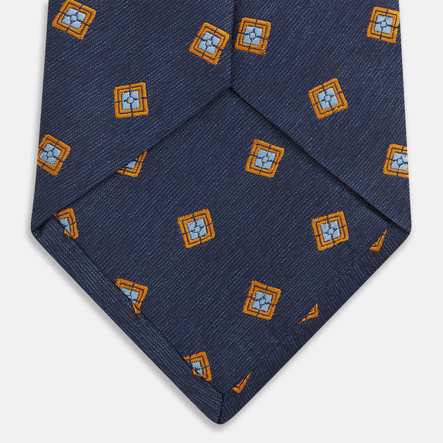 View 4 of product The Turnbull & Asser Orange Multi Geo Silk Tie, featuring a vibrant geometric pattern, is showcased rolled up on a plain white background—an elegant piece from our autumn-winter collection.