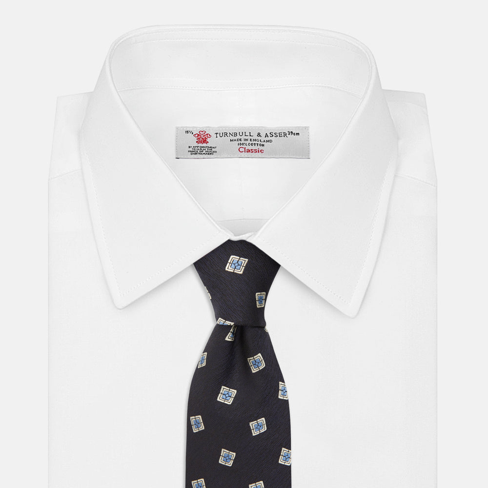 The Turnbull & Asser Navy Multi Geo Silk Tie features a dark navy blue geometric pattern with blue and cream squares—ideal for pairing with bold signature shirts from the autumn-winter collection.