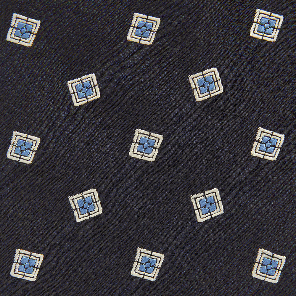 The Turnbull & Asser Navy Multi Geo Silk Tie features a dark navy blue geometric pattern with blue and cream squares—ideal for pairing with bold signature shirts from the autumn-winter collection.