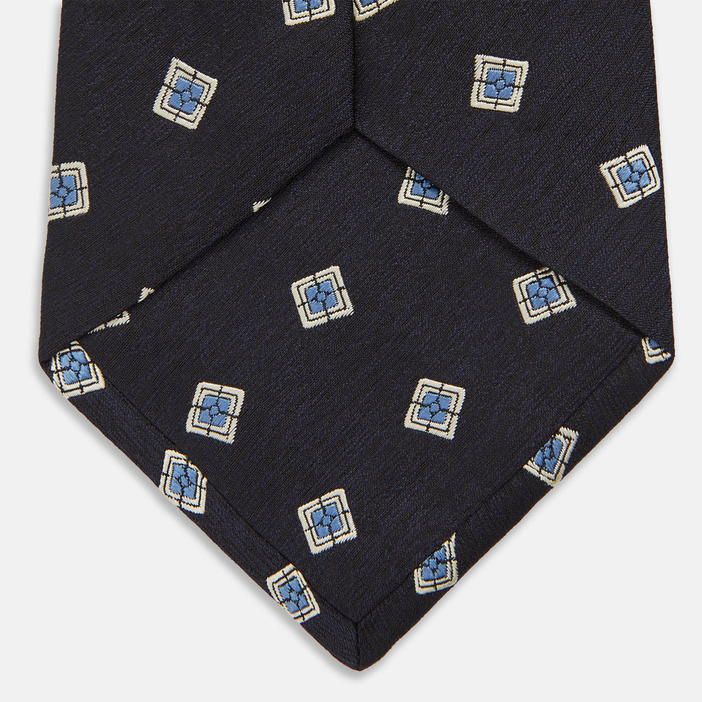 The Turnbull & Asser Navy Multi Geo Silk Tie features a dark navy blue geometric pattern with blue and cream squares—ideal for pairing with bold signature shirts from the autumn-winter collection.