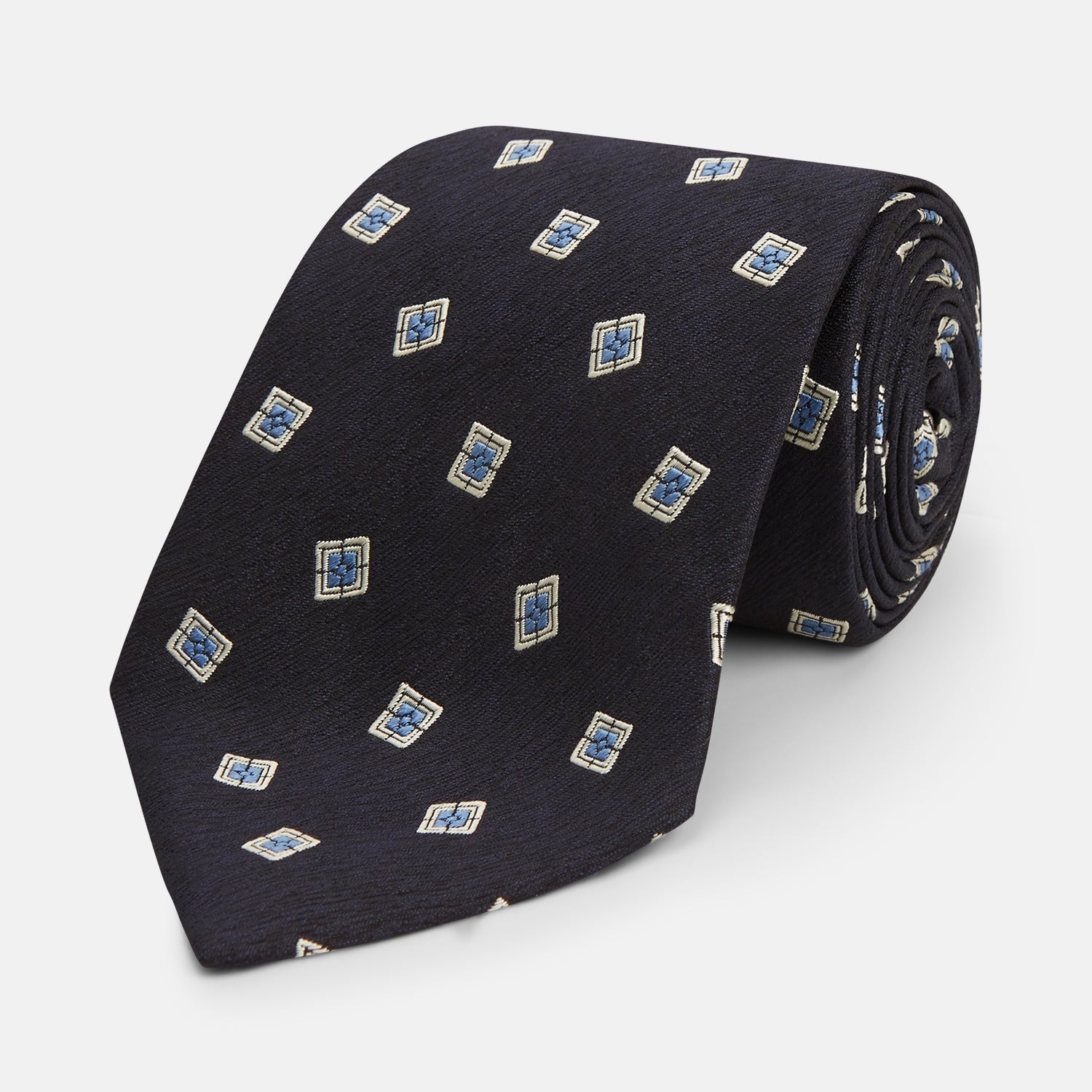 View 1 of product The Turnbull & Asser Navy Multi Geo Silk Tie features a dark navy blue geometric pattern with blue and cream squares—ideal for pairing with bold signature shirts from the autumn-winter collection.