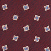 View 3 of product The Turnbull & Asser Burgundy Multi Geo Silk Tie features burgundy silk with blue, white, and yellow geometric designs—ideal for bold statement shirts. Shown rolled against a plain white background.