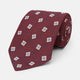 The Turnbull & Asser Burgundy Multi Geo Silk Tie features burgundy silk with blue, white, and yellow geometric designs—ideal for bold statement shirts. Shown rolled against a plain white background.