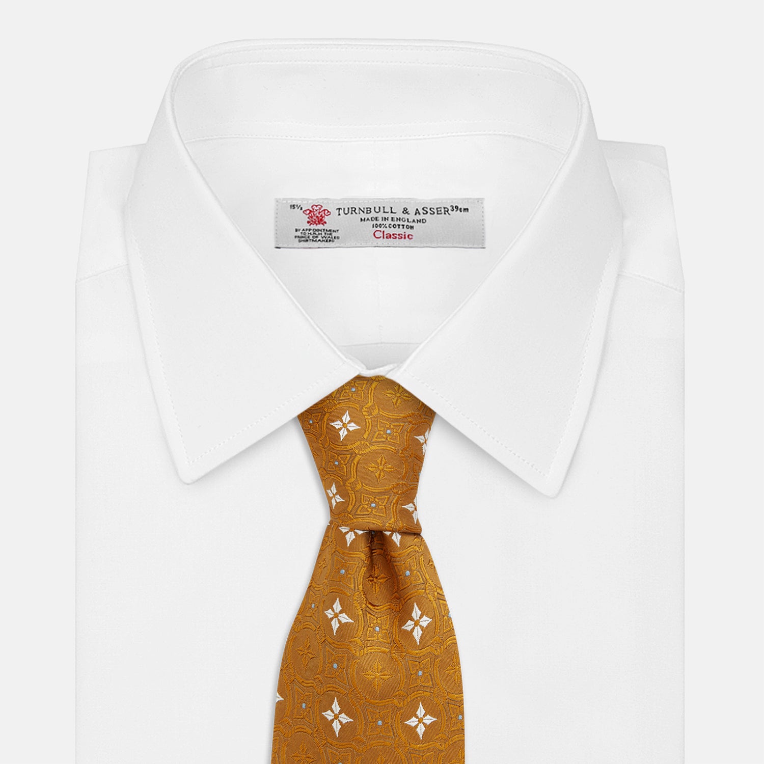 View 2 of product The Orange Multi Neat Silk Tie by Turnbull & Asser, from the autumn-winter collection, features a golden yellow geometric pattern on textured silk. Shown rolled on a white background, it pairs perfectly with bold signature shirts.