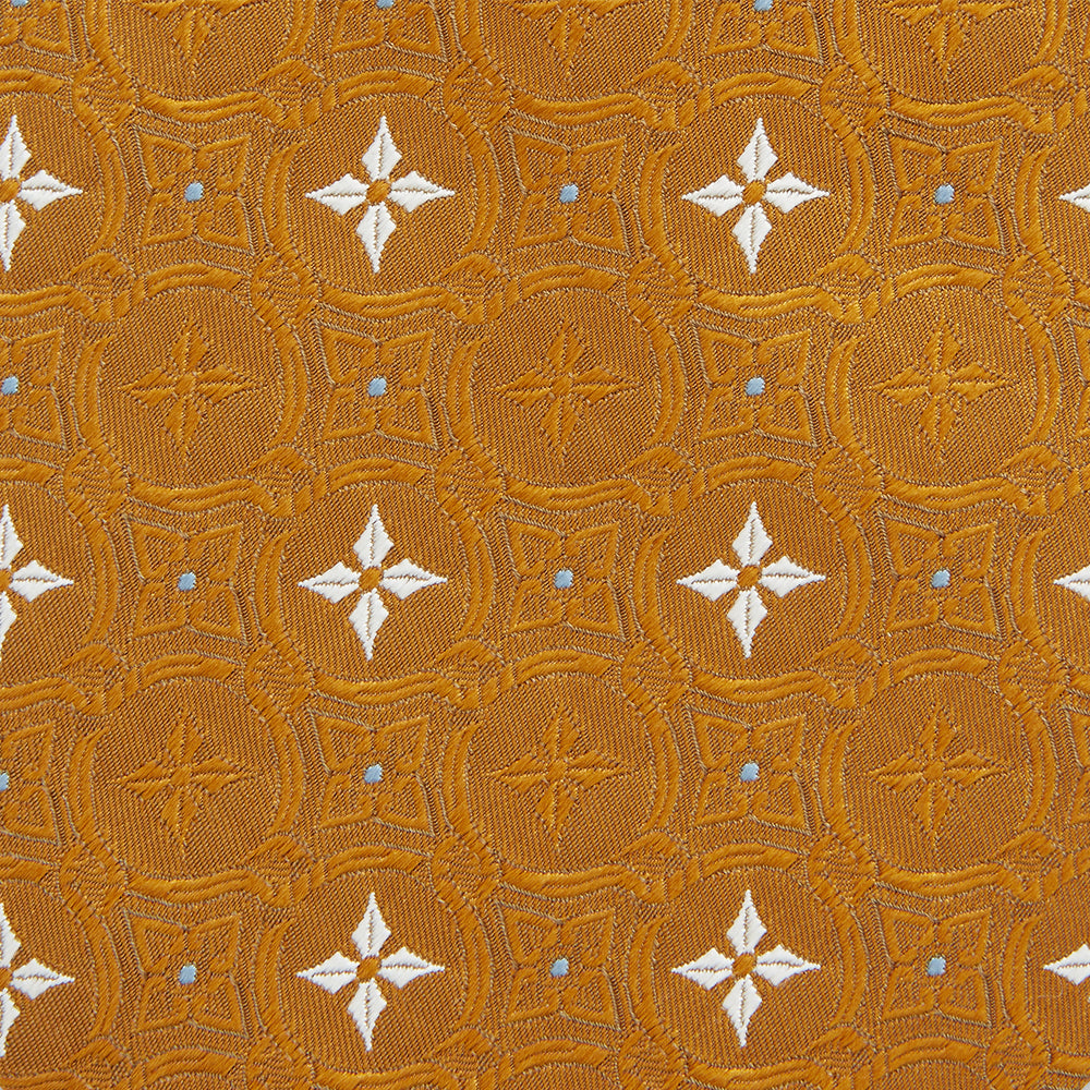 The Orange Multi Neat Silk Tie by Turnbull & Asser, from the autumn-winter collection, features a golden yellow geometric pattern on textured silk. Shown rolled on a white background, it pairs perfectly with bold signature shirts.