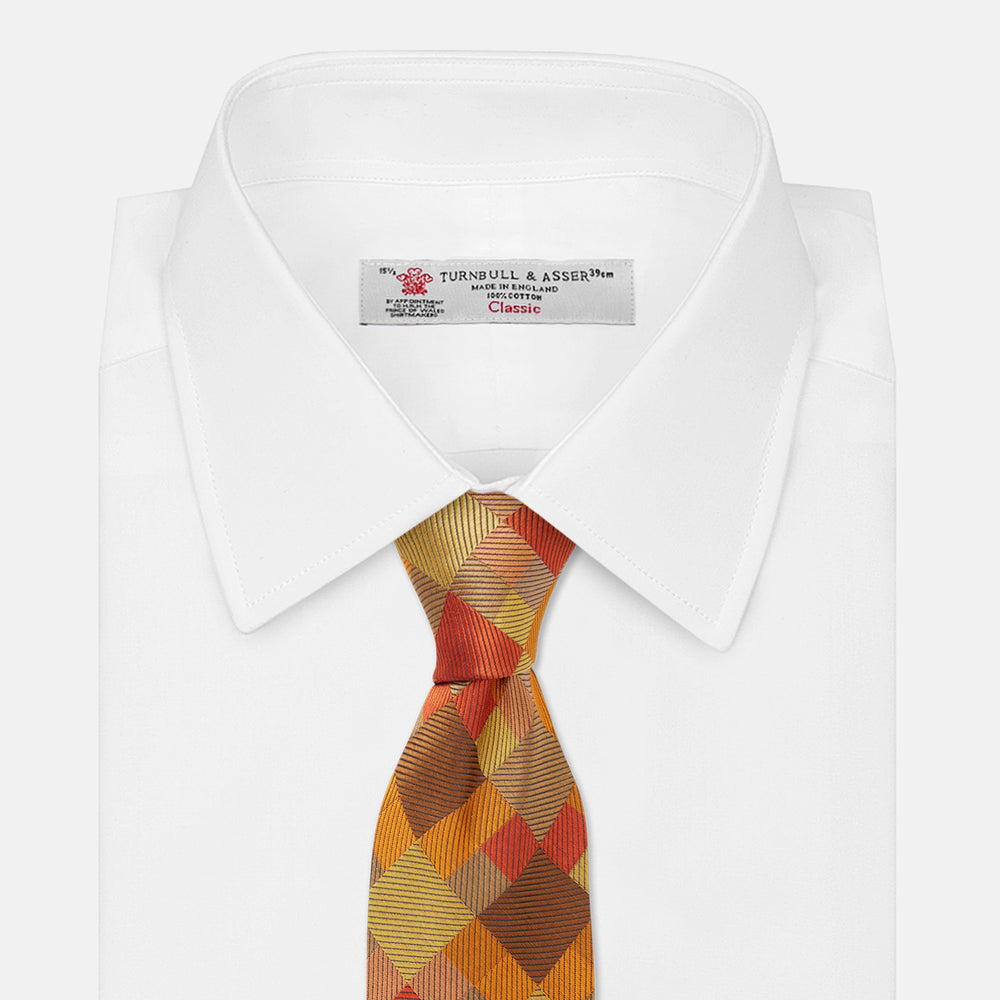 A close up of the Turnbull & Asser Orange Multi Pixel Silk Tie, featuring a refined checked design—ideal for elevating your autumn-winter style.