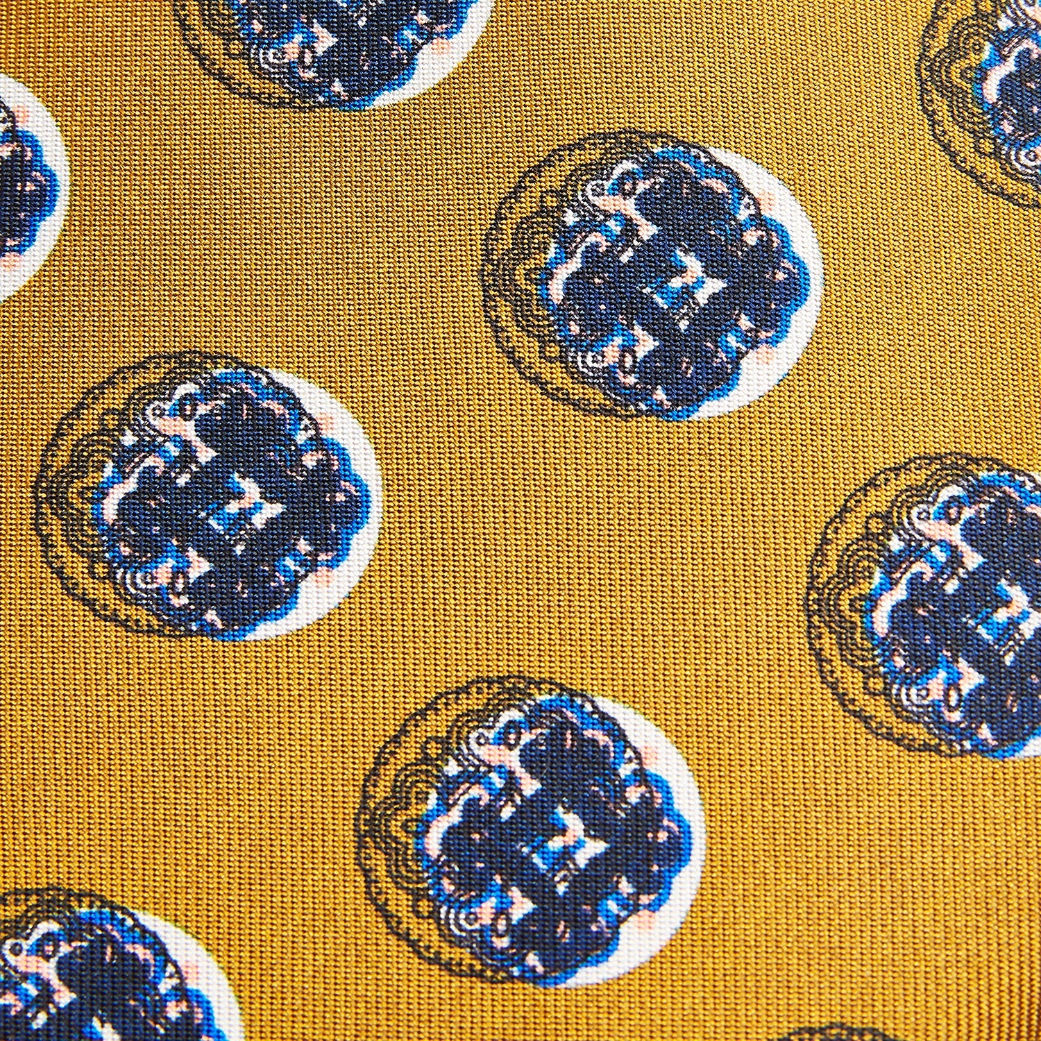 View 3 of product A rolled-up Turnbull & Asser Gold Shadow Spot Printed Silk Tie, featuring blue and white circular patterns on fine Adamley Macclesfield silk, displayed against a white background.