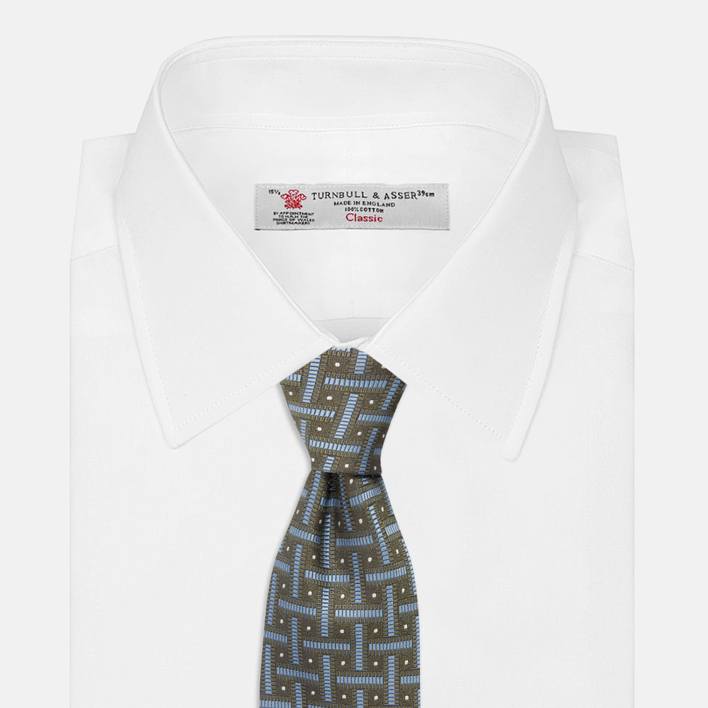 The Turnbull & Asser Green & Navy Cross Silk Tie features an olive green base with navy geometric patterns and white dots, shown rolled on a light surface—an ideal accessory to elevate any formal look.