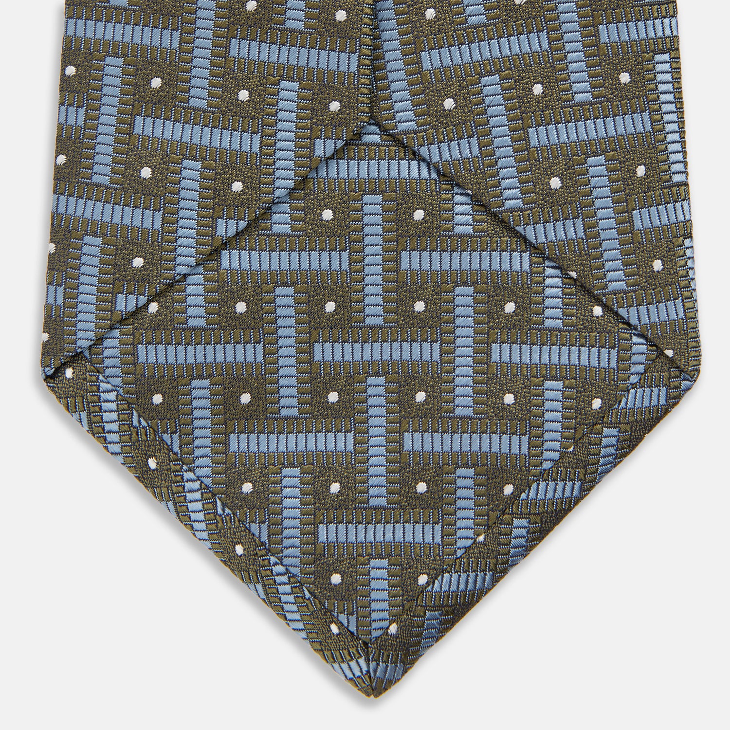 View 4 of product The Turnbull & Asser Green & Navy Cross Silk Tie features an olive green base with navy geometric patterns and white dots, shown rolled on a light surface—an ideal accessory to elevate any formal look.