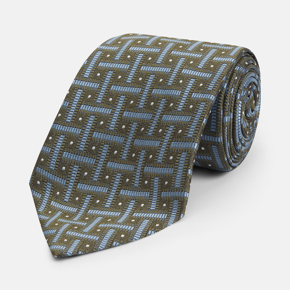 The Turnbull & Asser Green & Navy Cross Silk Tie features an olive green base with navy geometric patterns and white dots, shown rolled on a light surface—an ideal accessory to elevate any formal look.