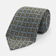 The Turnbull & Asser Green & Navy Cross Silk Tie features an olive green base with navy geometric patterns and white dots, shown rolled on a light surface—an ideal accessory to elevate any formal look.