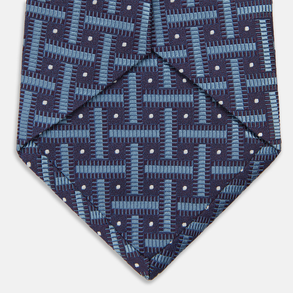 The Turnbull & Asser Navy & Blue Cross Silk Tie features a navy silk base with light blue and white geometric patterns and small white dots—ideal for elevating formal looks or pairing with signature shirts.