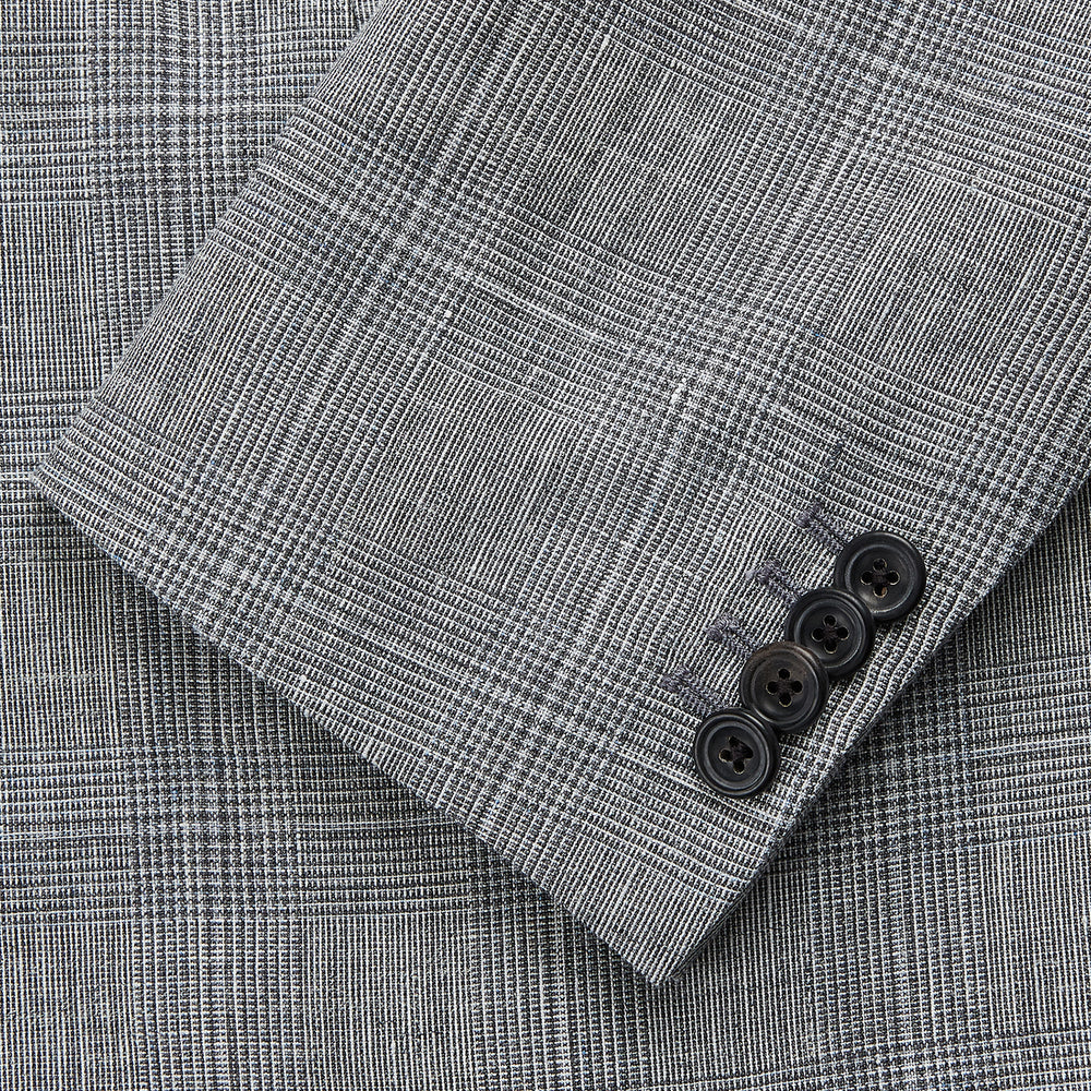 The Turnbull & Asser Grey Multi Check Linen Blend Barrington Blazer features notched lapels, a two-button single-breasted front, flap pockets, and buttoned cuffs, shown against a plain white background.