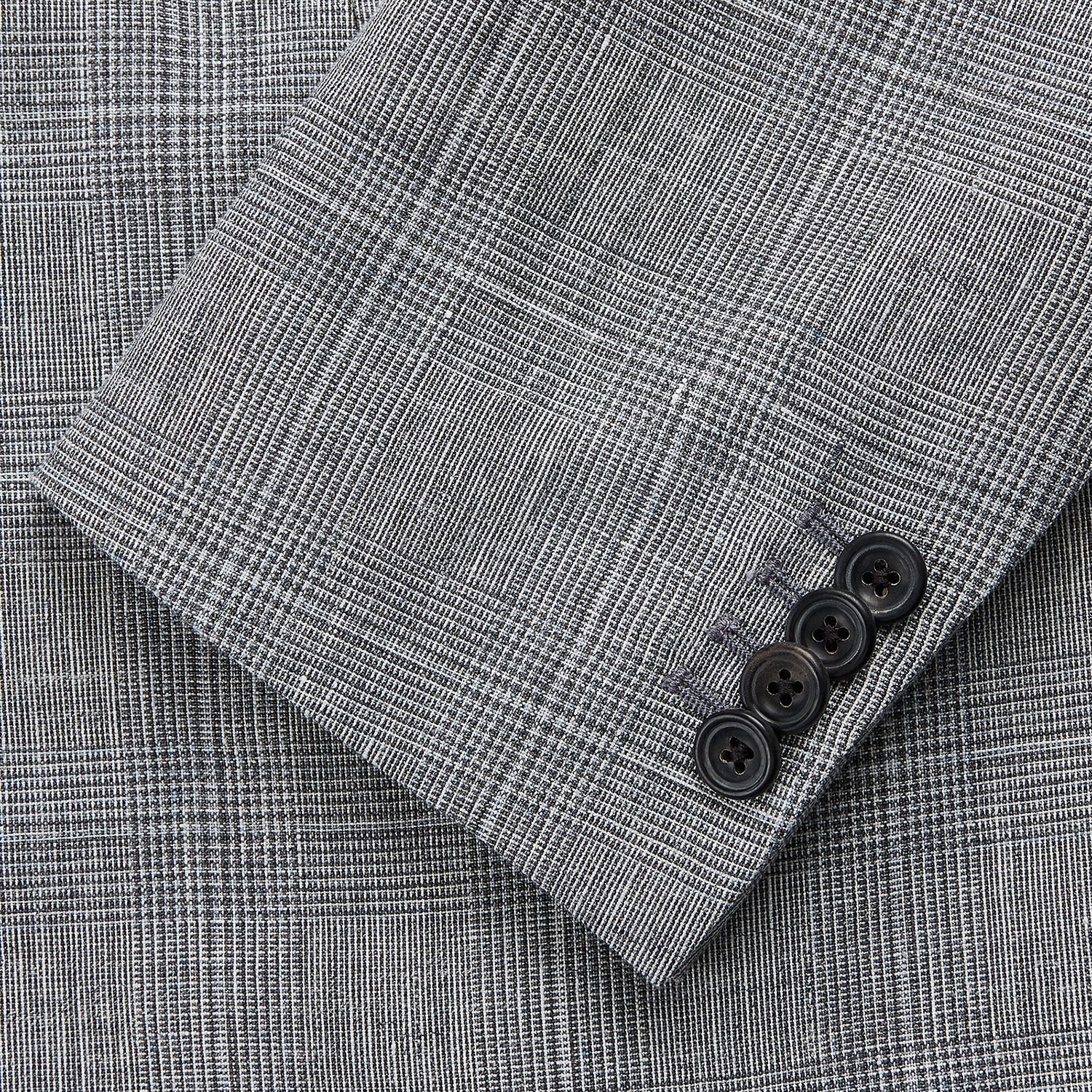 View 3 of product The Turnbull & Asser Grey Multi Check Linen Blend Barrington Blazer features notched lapels, a two-button single-breasted front, flap pockets, and buttoned cuffs, shown against a plain white background.