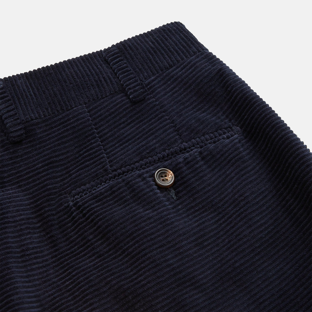 A pair of Turnbull & Asser Navy Horizontal Cord Nolan Trousers featuring a straight-leg fit, button and zip closure, front pleats, and classic horizontal cord texture, laid flat on a white background.