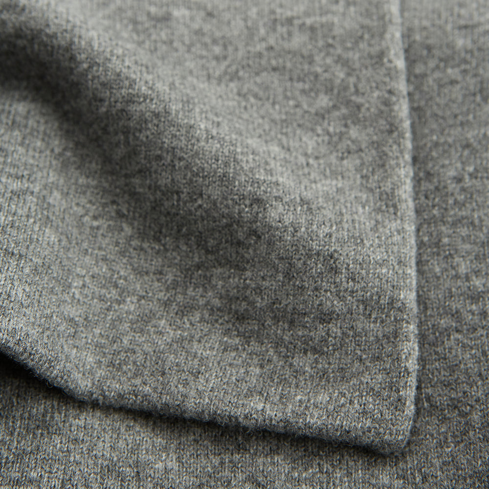 The Pale Blue Wool and Cashmere Lily Blanket by Turnbull & Asser features abstract, hand-drawn designs in blue, yellow, and gray on a white background.