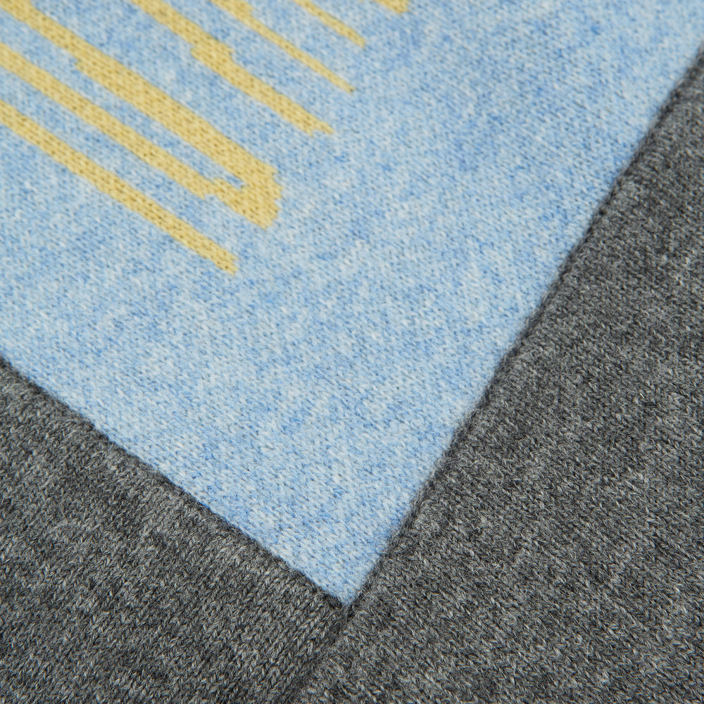 The Pale Blue Wool and Cashmere Lily Blanket by Turnbull & Asser features abstract, hand-drawn designs in blue, yellow, and gray on a white background.