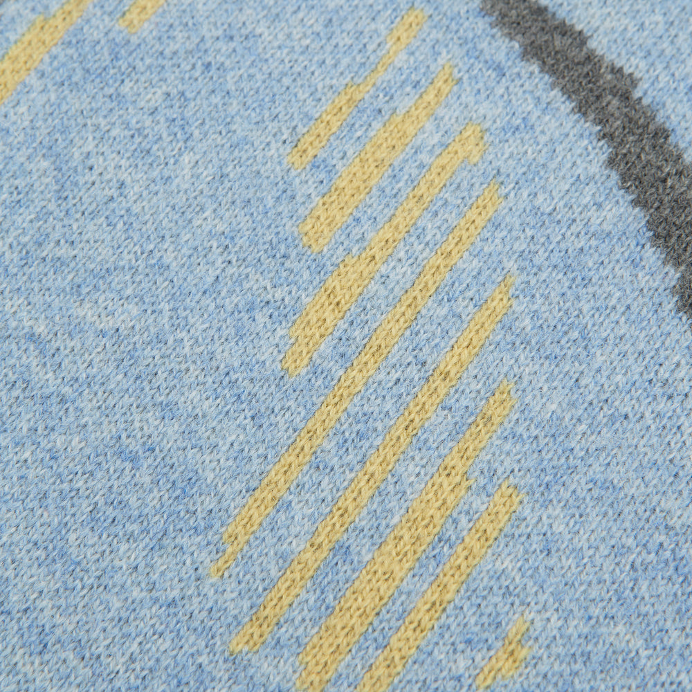 The Pale Blue Wool and Cashmere Lily Blanket by Turnbull & Asser features abstract, hand-drawn designs in blue, yellow, and gray on a white background.