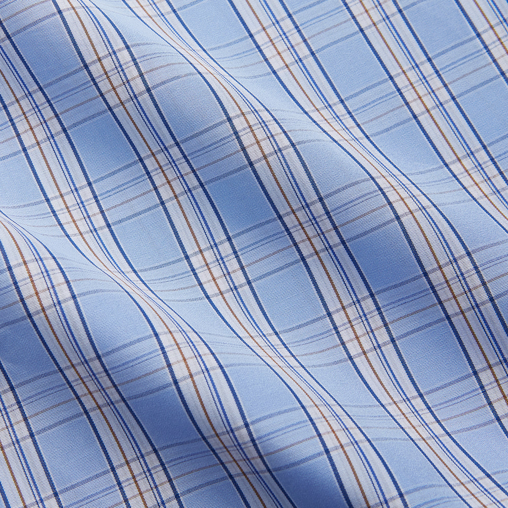 The Turnbull & Asser Pale Blue Multi Check Cotton Sussex Nightshirt features a classic plaid pattern, brown piping accents, button-down front, chest pocket, and curved hem—a timeless long-sleeve sleepwear essential.