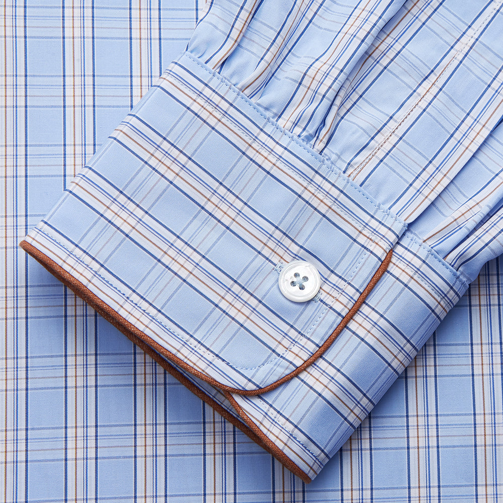 The Turnbull & Asser Pale Blue Multi Check Cotton Sussex Nightshirt features a classic plaid pattern, brown piping accents, button-down front, chest pocket, and curved hem—a timeless long-sleeve sleepwear essential.