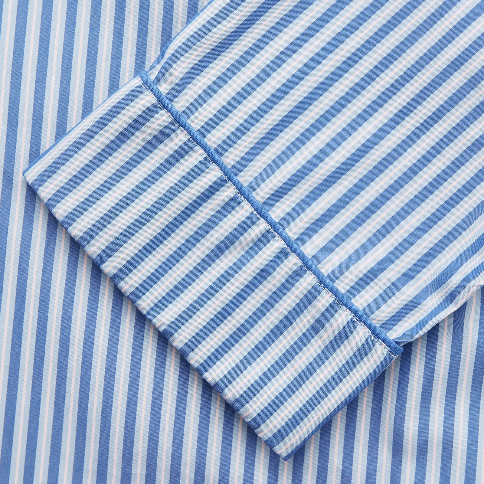View 3 of product The Blue Multi Cotton Hyde Pyjama Set by Turnbull & Asser features a long-sleeve button-up top with chest pocket and matching elastic waist pants in blue and white stripes, crafted from soft Italian cotton and displayed on a white background.